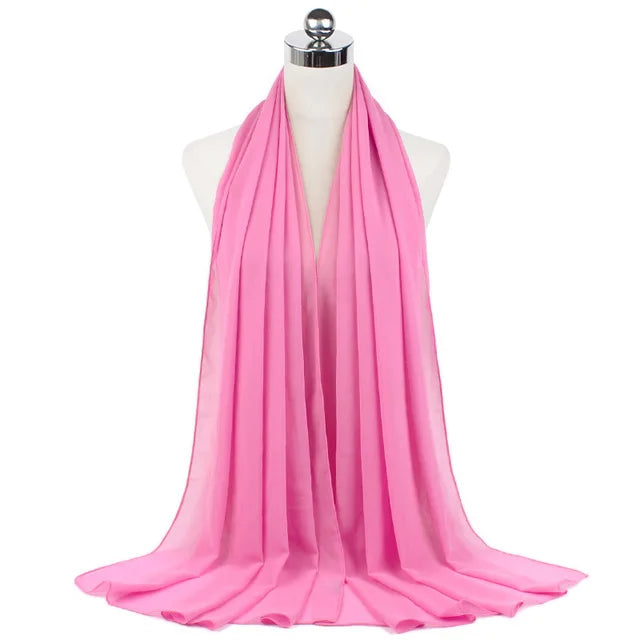 A bright pink chiffon hijab scarf draped around a mannequin's neck.