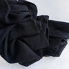 Foulard hijab noir en coton viscose souple avec une pompon sur une surface blanche.