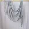 Hijab de encaje gris claro con estampado doble, drapeado sobre un perchero dorado.