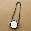 Collar de cadena plateada con colgante circular acolchado blanco y negro.