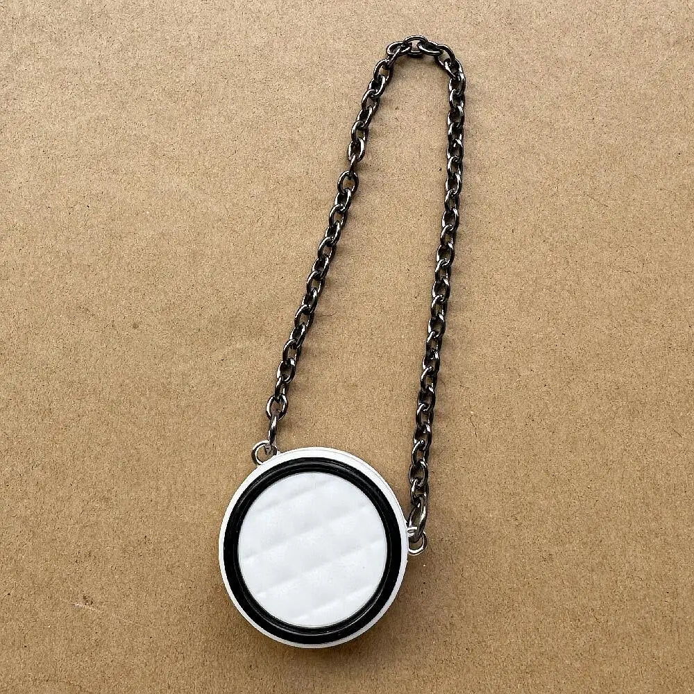 Collar de cadena plateada con colgante circular acolchado blanco y negro.