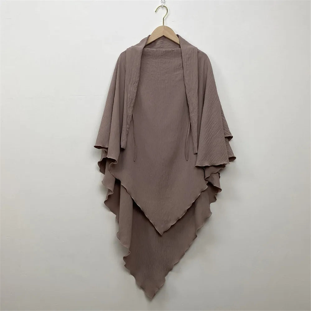 A mauve two-layer everyday hijab scarf draped on a wooden hanger against a white wall.
