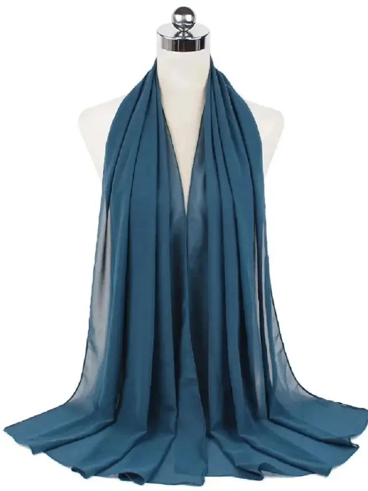 Ein tealfarbener Chiffon-Hijab-Schal, um den Hals einer Mannequin drapiert.