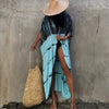 Person in light blue patterned kimono cover-up dress and straw hat against a textured gray wall