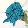 A teal silk satin hijab scarf draped over a white fluffy surface.
