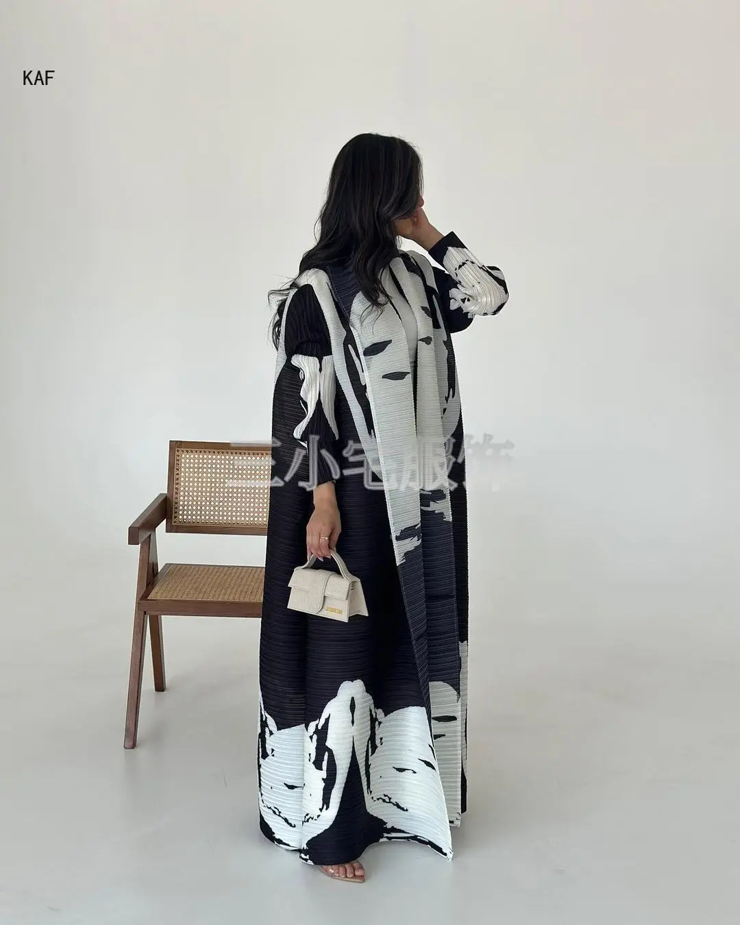 Une femme portant une veste coupe-vent plissée à imprimé rétro noir et blanc, debout sur un fond blanc.