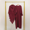 A maroon abaya and khimar set displayed on a gold hanger against a light background.