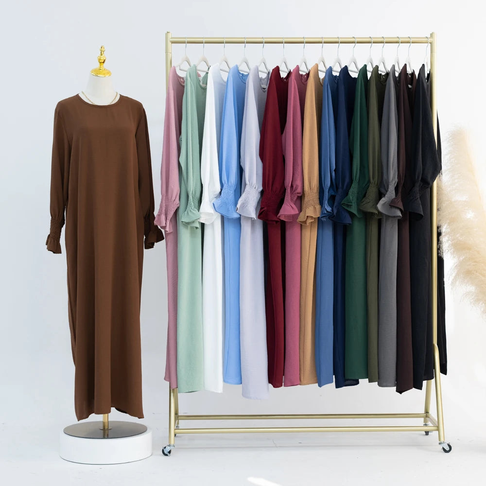Vestido abaya marrón holgado con puños fruncidos, exhibido en percha dorada.