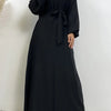 Eine Frau trägt einen schwarzen marokkanischen Kaftan-Abaya mit langen Ärmeln und einem zugebundenen Bund.