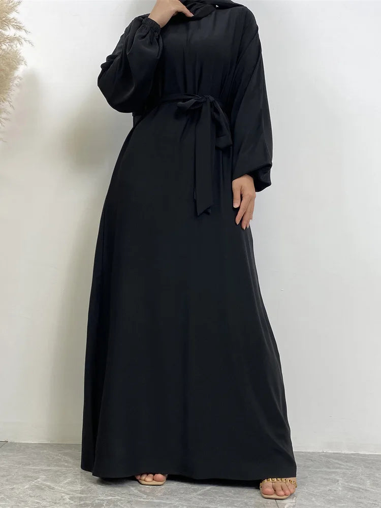 Eine Frau trägt einen schwarzen marokkanischen Kaftan-Abaya mit langen Ärmeln und einem zugebundenen Bund.