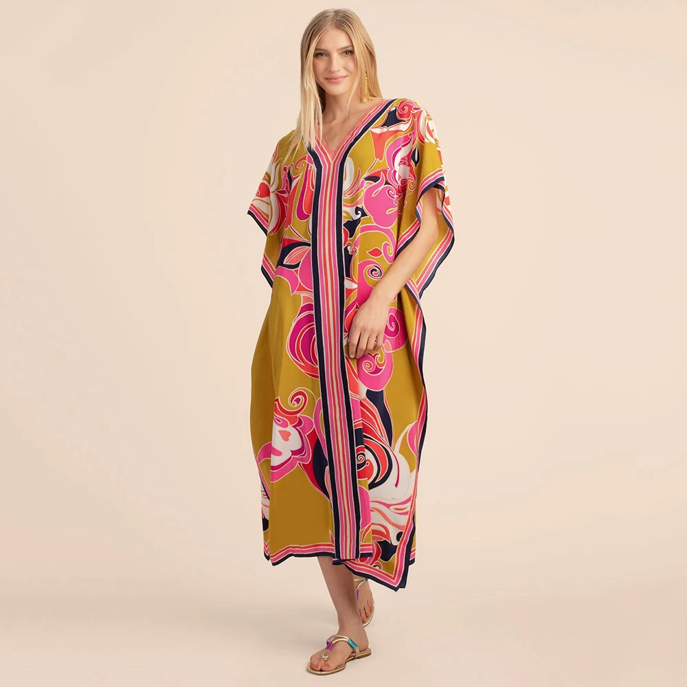 Eine Frau modelliert ein gelbes marokkanisches Batwing Kaftan-Überkleid mit rosa und lila Blumenmustern.