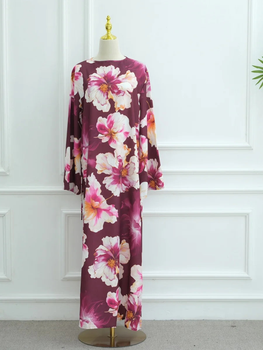 Langes dunkelrotes Abaya-Kleid mit Blumenmuster aus rosa und weißen Pfingstrosen auf einem Mannequin.