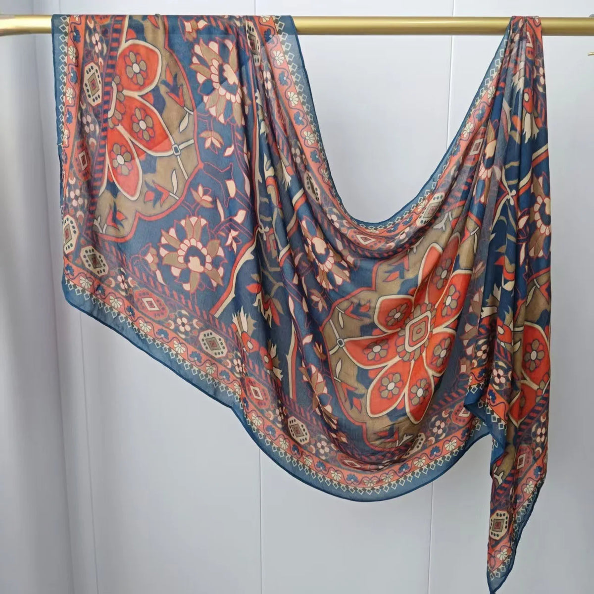 Fließender, mehrfarbiger Hijab-Schal mit floralen Mustern an einem Holzstab.