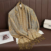 Pañuelo de pashmina lujoso estampado beige y dorado sobre un sofá de cuero marrón.