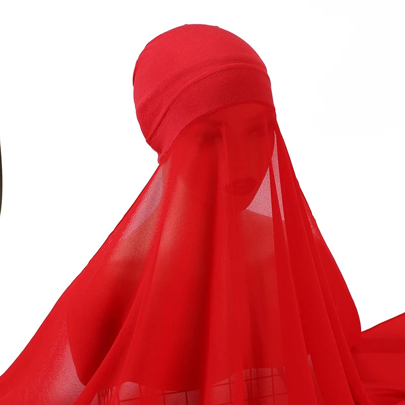 Un conjunto de hijab y chal de gasa rojo brillante drapeado sobre la cabeza y los hombros de una persona.