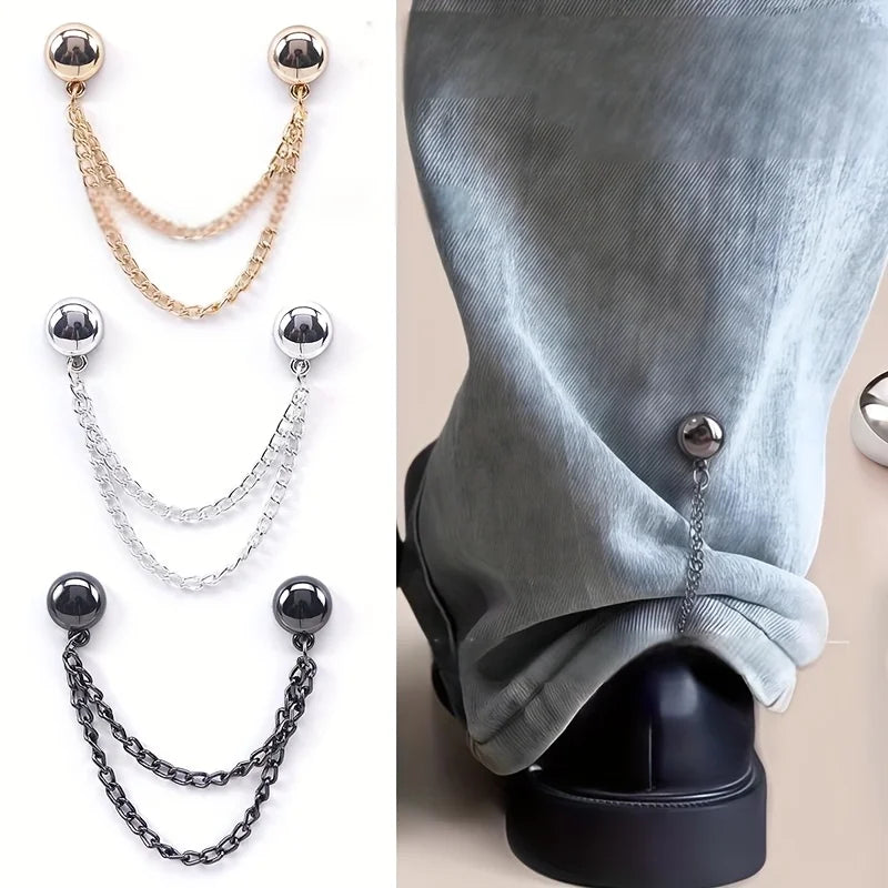 Un juego de seis clips de ropa magnéticos en cadenas doradas, plateadas y negras, mostrados contra una manga de tela gris.