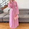 A woman wearing a long pink elegant two-piece Arabic modest set with long sleeves and floral accents.