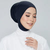 Une femme portant un foulard niqab bleu marine uni et des vêtements blancs, souriant légèrement.