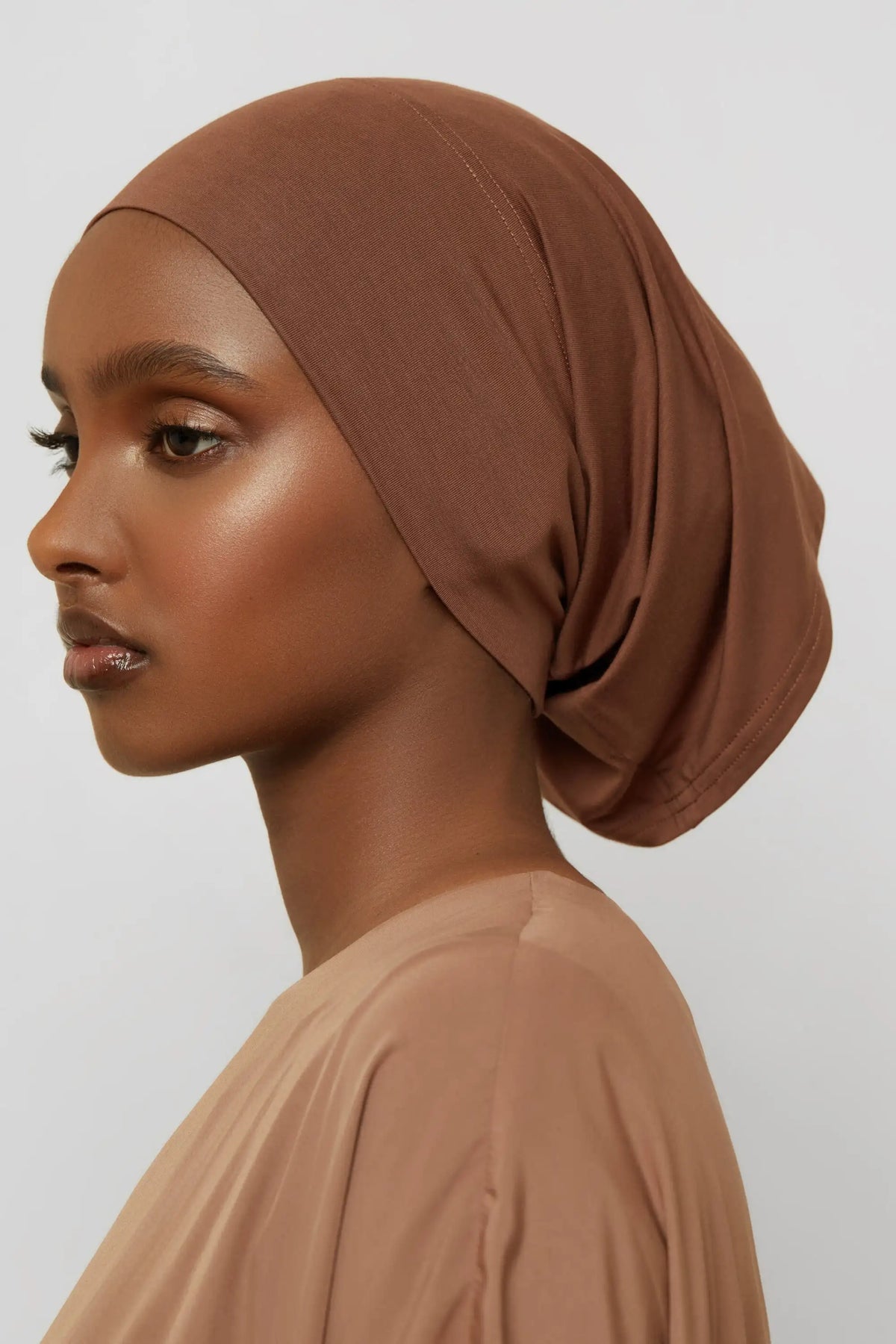 Model trägt eine bordeauxbraune Bambus-Jersey-Hijabkappe und passendes Oberteil.