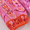 Pink fabric with orange floral print showing a gathered cuff detail on a dress sleeve.