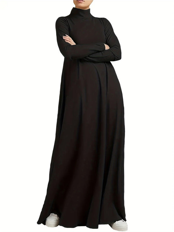 A woman wearing a solid black loose fit maxi dress with a high neck and long sleeves.