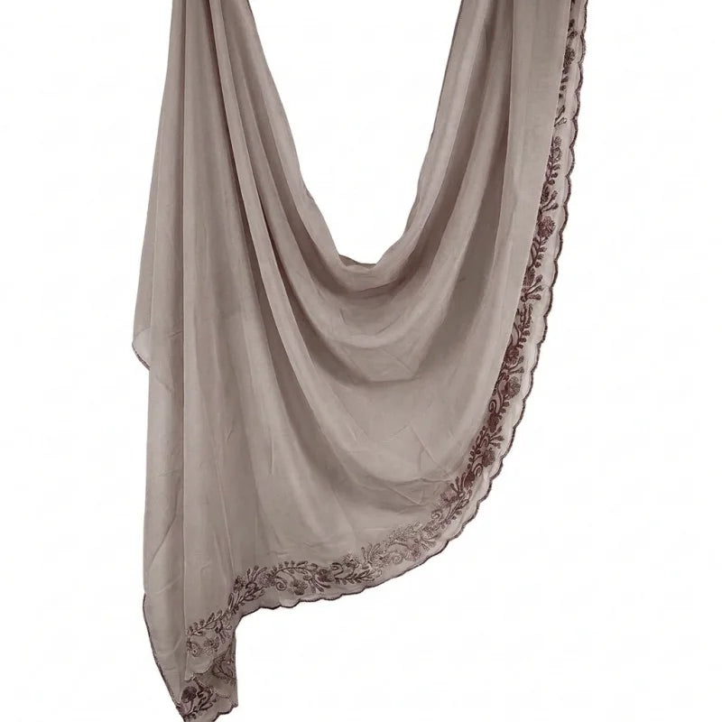 Foulard hijab en mousseline beige doux avec bordour de faux cils, drapé verticalement.