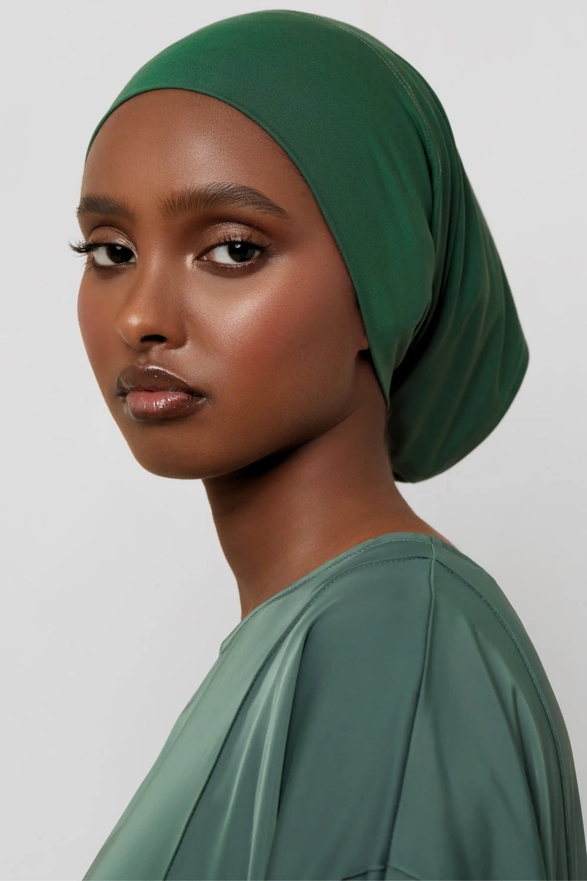 Model wearing a deep emerald green bamboo jersey tube hijab cap.