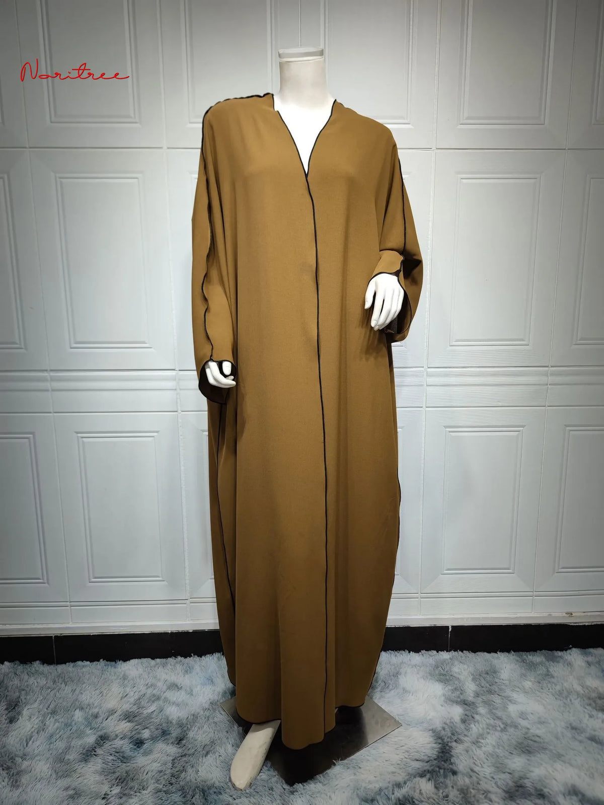 Vestido abaya oversize color marrón olivo, mostrado en maniquí contra pared blanca con paneles.