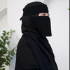 Eine Frau mit schwarzem, atmungsaktivem Mesh-Hijab und Halsband, Profilansicht.