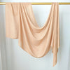 Un foulard modal beige uni et fluide drapé sur un cintre or contre un fond blanc.