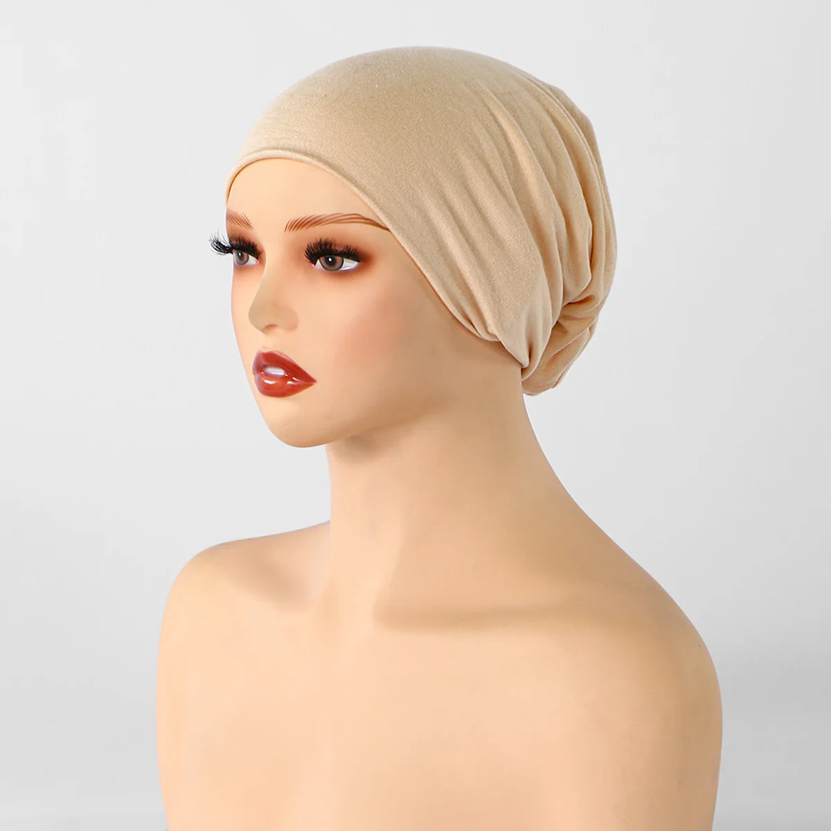 Gorra interior de pañuelo de punto beige mostrada en un maniquí de cabeza.