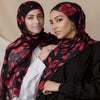Dos mujeres vistiendo pañuelos de hijab negros con estampado floral acuarela roja y tops negros.