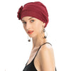 Eine Frau trägt eine tiefrote, floral bestickte Hijab-Turbanmütze mit silbernen Creolenohrringen.