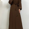 Eine Frau trägt eine lange, dunkelbraune marokkanische Kaftan-Abaya mit schwarzen Ärmeln und einem passenden Kopftuch.