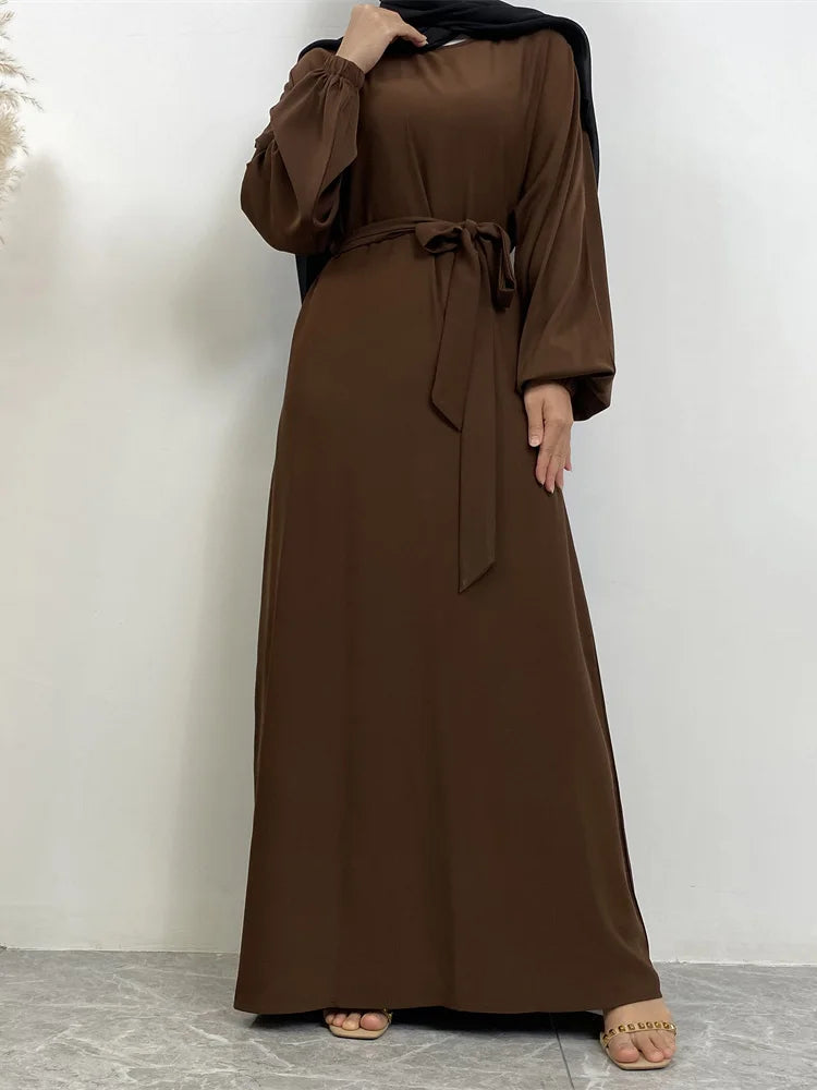 Eine Frau trägt eine lange, dunkelbraune marokkanische Kaftan-Abaya mit schwarzen Ärmeln und einem passenden Kopftuch.