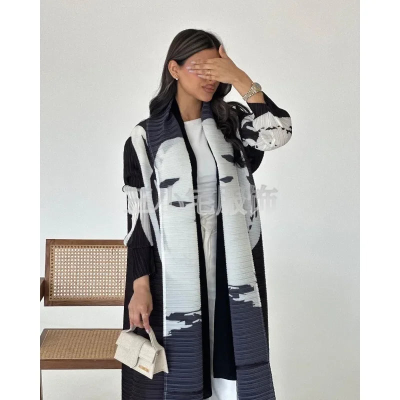 Une femme modélise une veste coupe-vent plissée noir et blanc avec une chemise blanche et un sac beige.