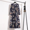 Dunkelblaue Boho-Blumenmuster-Maxikleid hängt an einem schwarzen Haken vor einer weißen Wand.