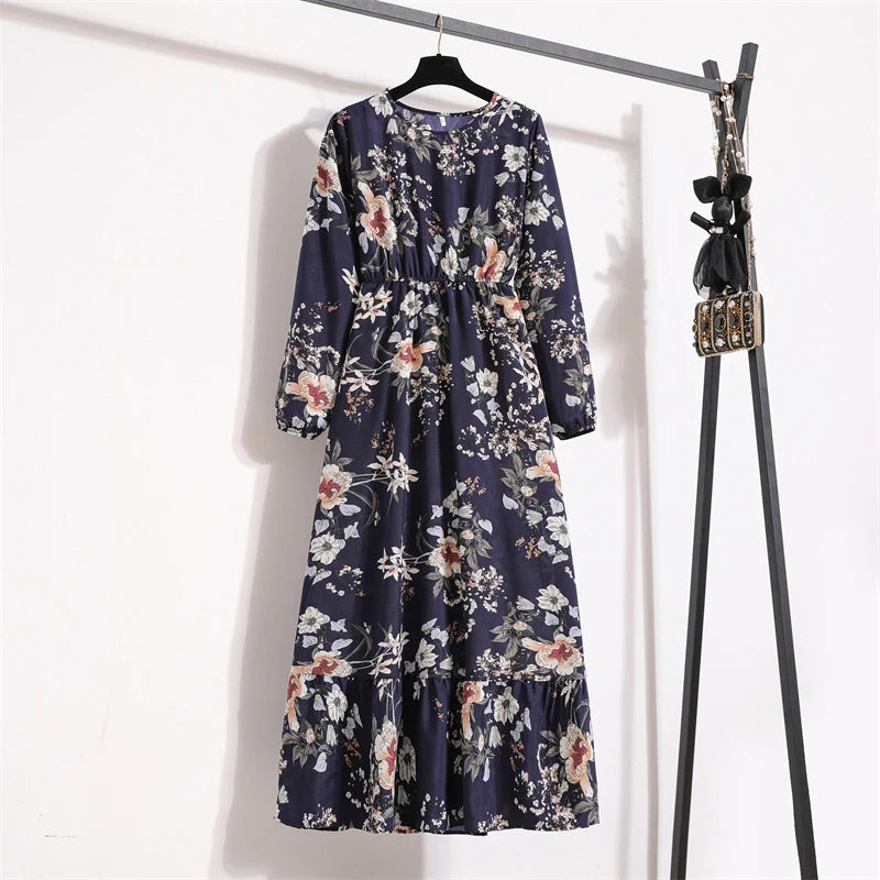 Dunkelblaue Boho-Blumenmuster-Maxikleid hängt an einem schwarzen Haken vor einer weißen Wand.