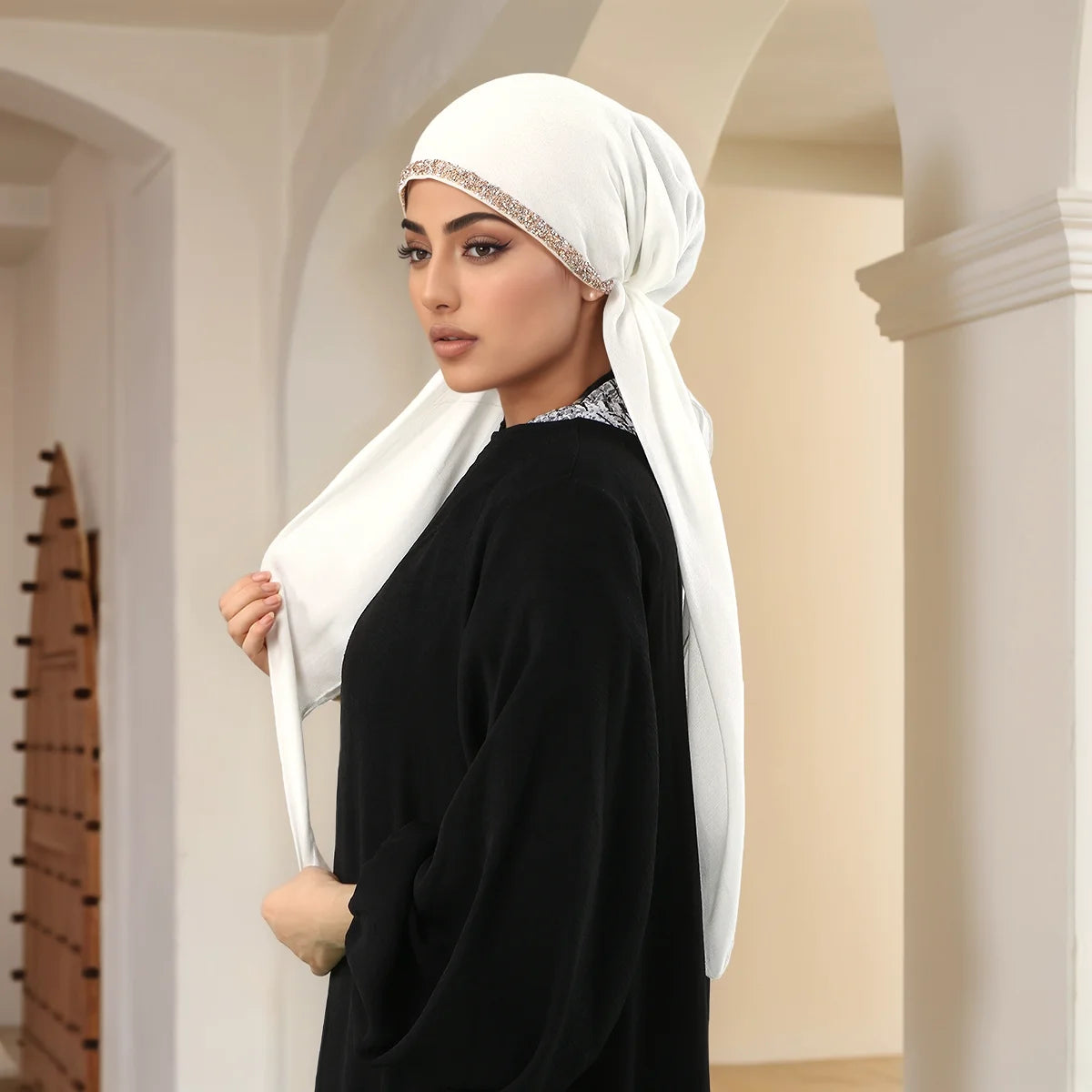 Une femme portant un élégant foulard modal blanc avec des incrustations de diamants et une tenue noire.