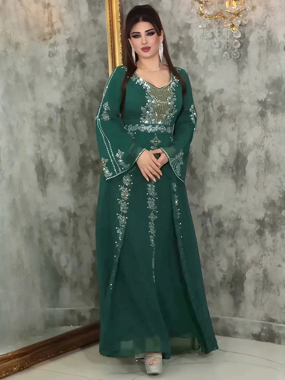 Eine Frau modelliert ein elegantes türkis-Chiffon-Abaya-Kleid mit filigranen silbernen Verzierungen und Rüschenärmeln vor ein