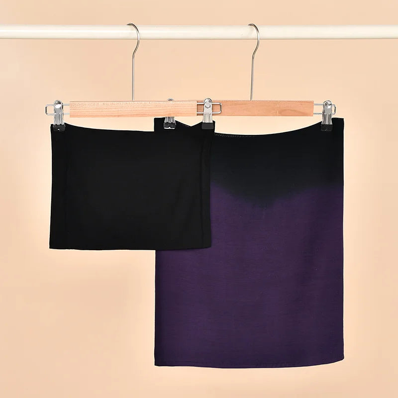 Écharpe modal hijab dégradé noir et violet, suspendue sur un cintre en bois.