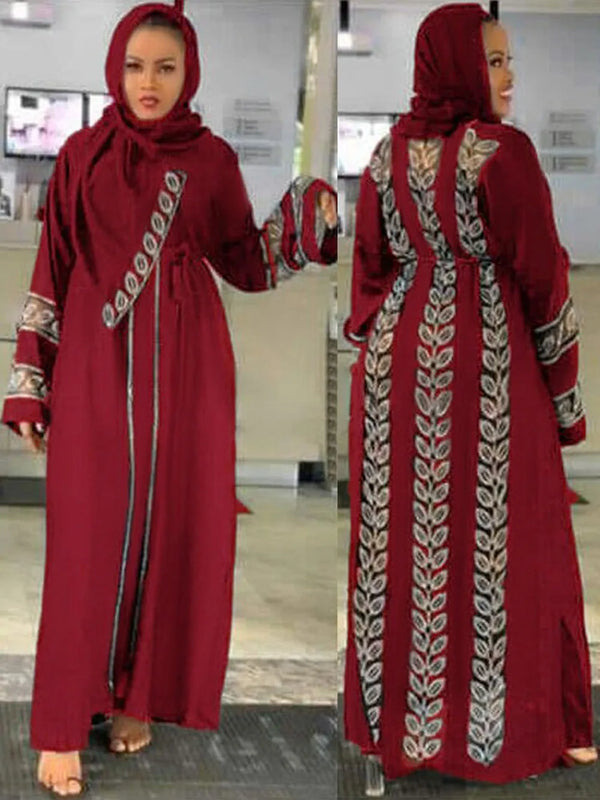A woman models a maroon abaya with silver embroidery and long sleeves.