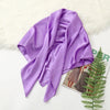 A purple silk satin hijab scarf draped over a white surface with a fluffy white rug.