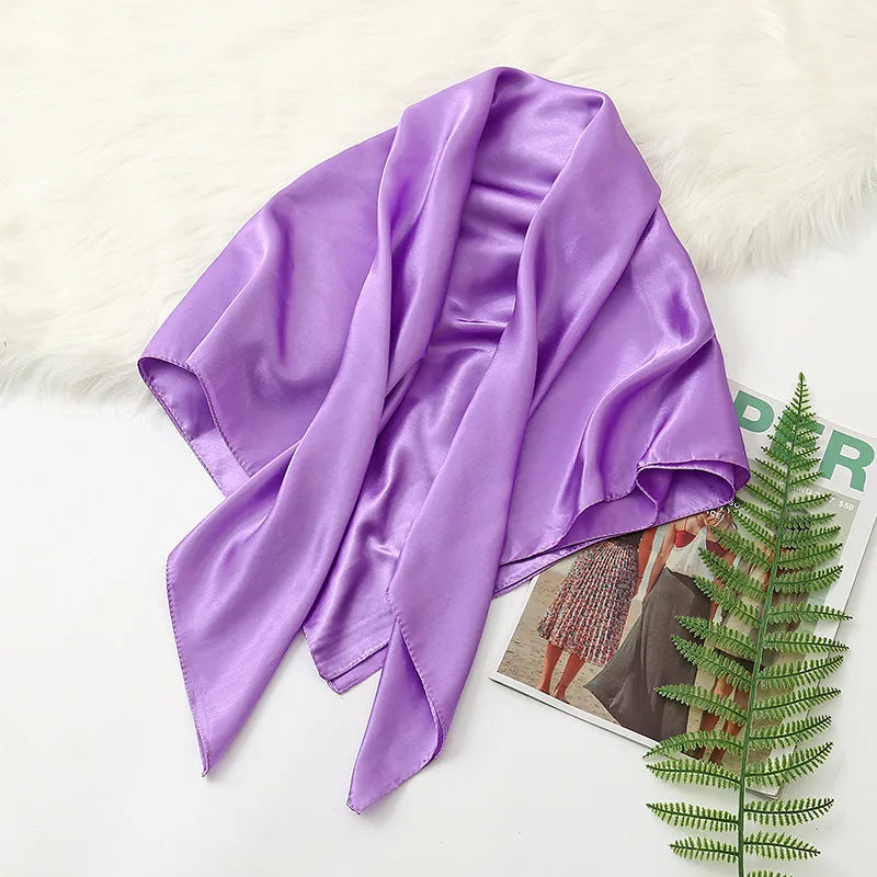 A purple silk satin hijab scarf draped over a white surface with a fluffy white rug.