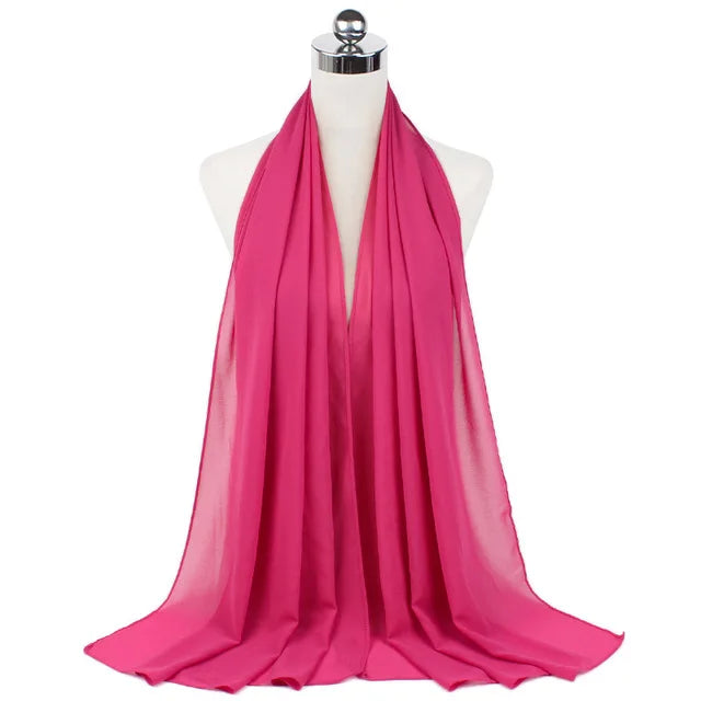 A vibrant pink chiffon hijab scarf draped around a mannequin's neck.