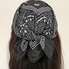 Foulard en coton à motif noir et blanc noué en nœud, porté dans les cheveux.