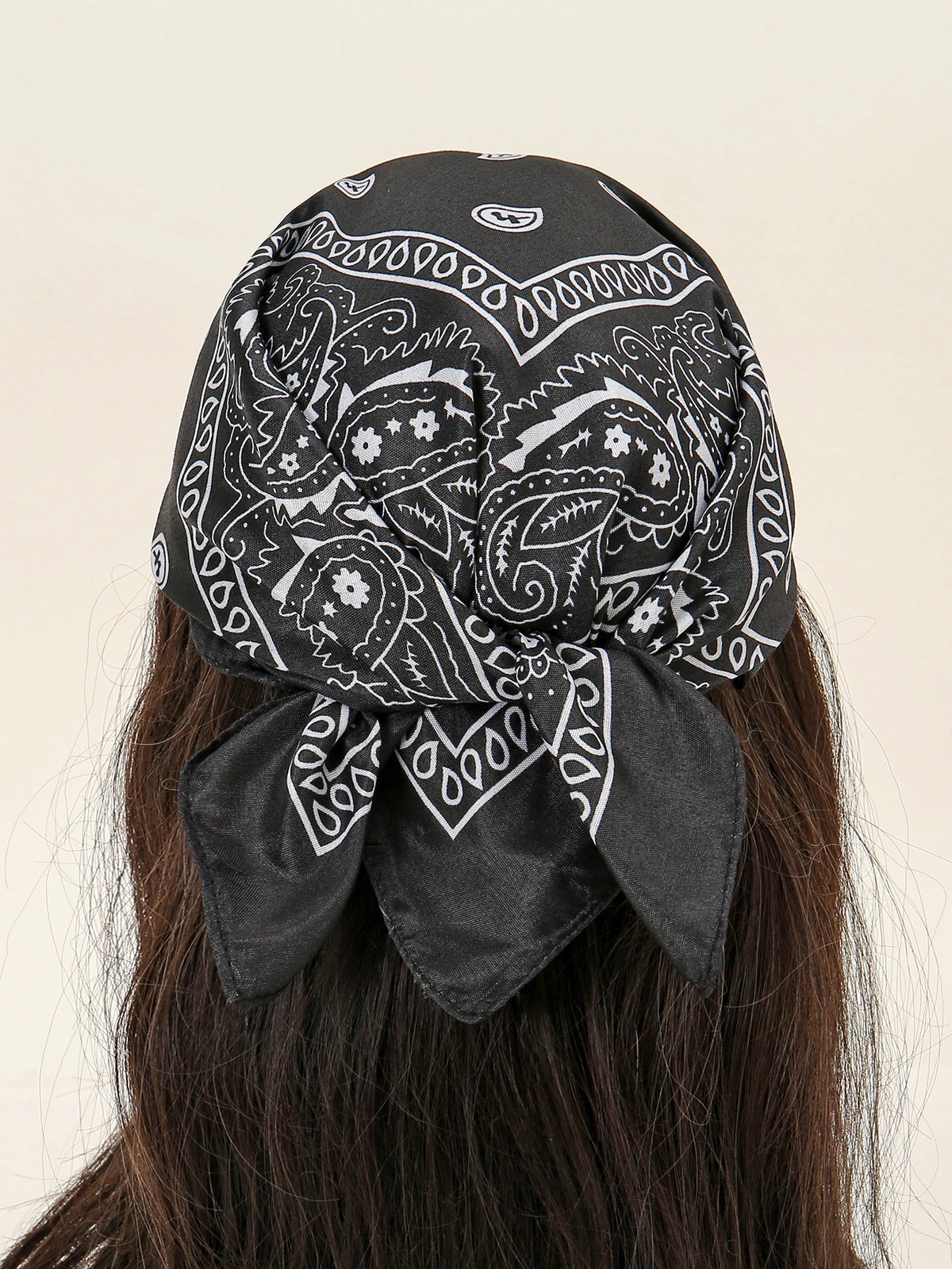 Foulard en coton à motif noir et blanc noué en nœud, porté dans les cheveux.