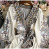 Weißes Blumen-Spitzen-Maxikleid mit aufwendiger Stickerei und V-Ausschnitt auf einem Bügel.