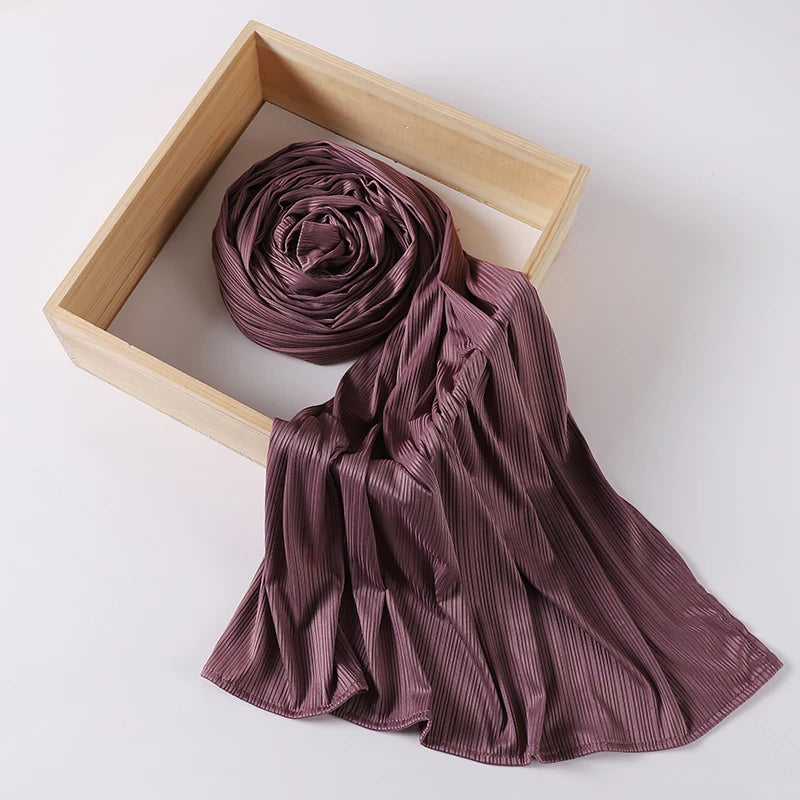 A mauve ribbed jersey hijab scarf is rolled and draped within a light wooden frame.