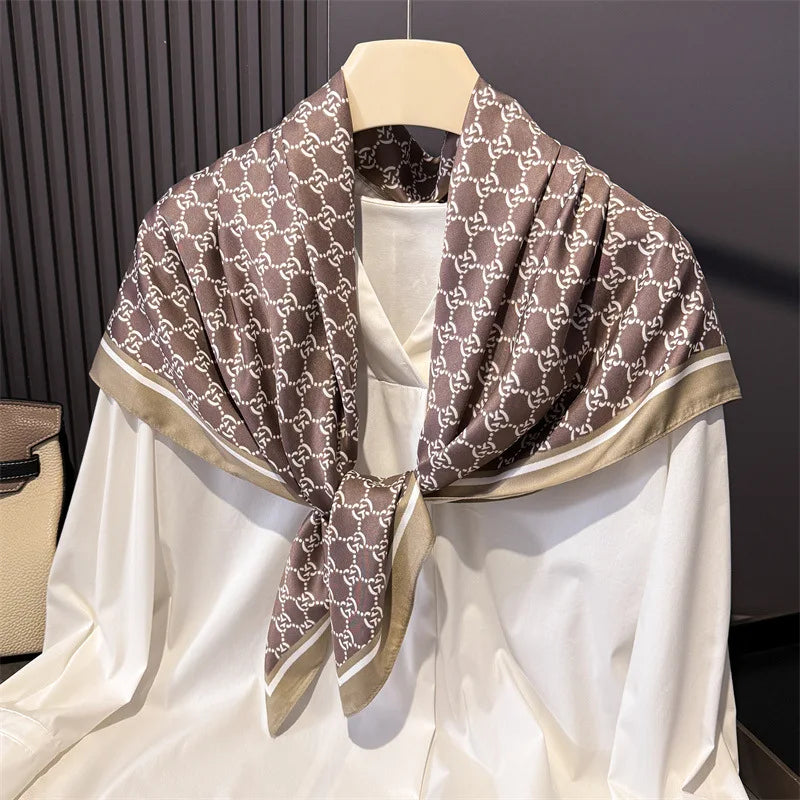 Beige und braunes Gucci-Print-Seiderschal, drapiert um ein weißes Kleidungsstück.